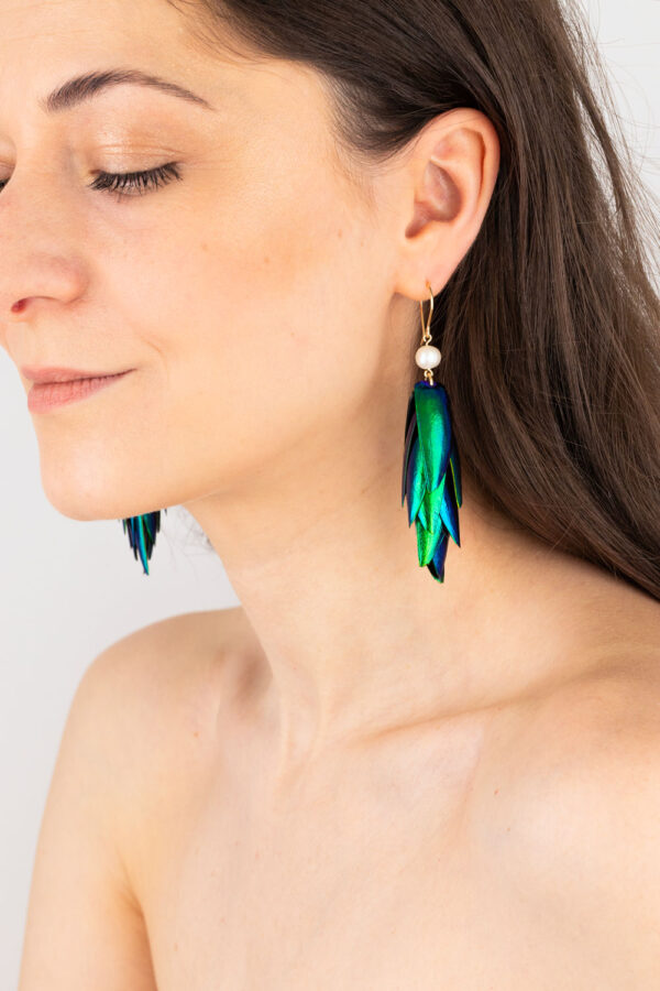 Pair of white pearl beetle earrings featured on a model