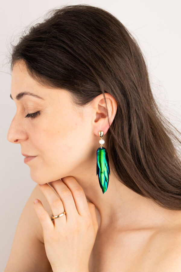 Close-up of peacock pearl beetle earrings showing colorful reflections